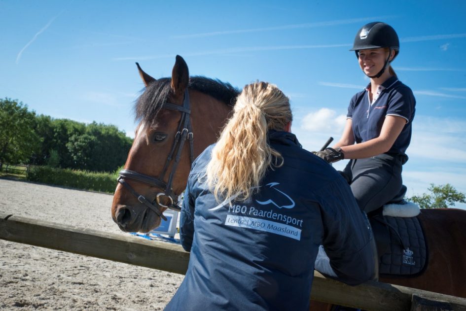 Student te paard en meisje bij hek