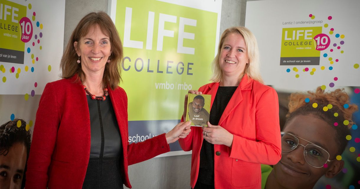 Wethouder van Aaken neemt boekje LIFE College in ontvangst