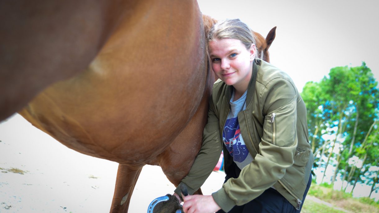 meisje krabt paardenhoef uit