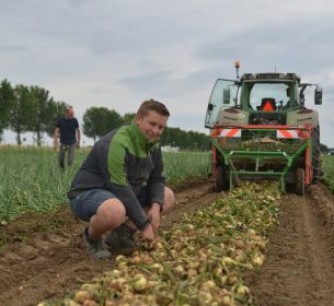 jongen zit naast gerooide uien