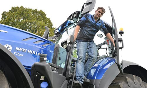 Loonwerker poseert bij een blauwe trekker