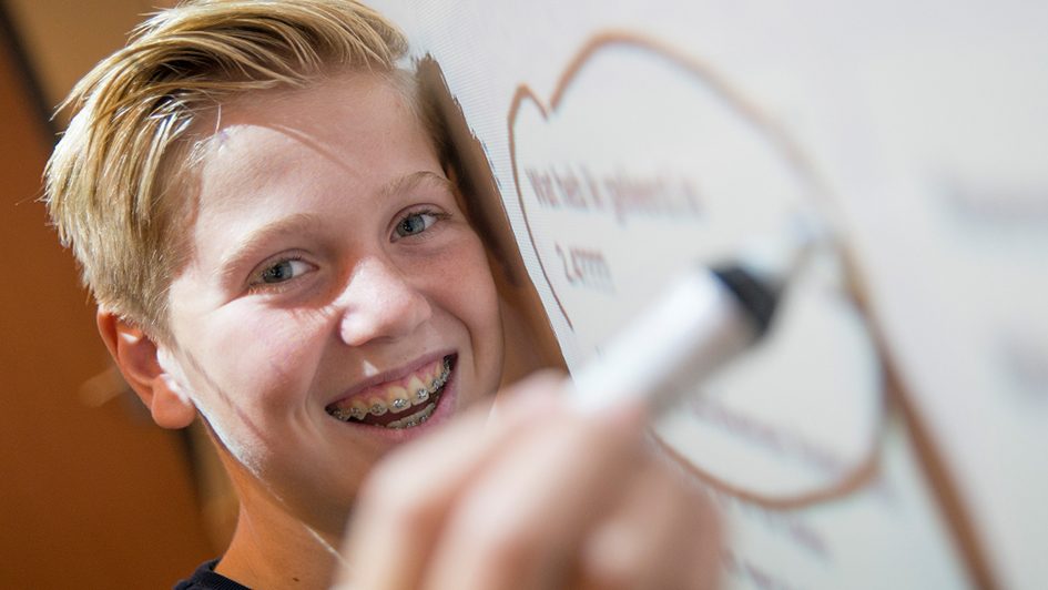 Leerling schrijft op digitaal bord.