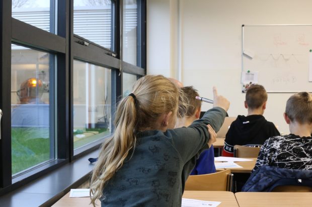 leerling in klas steekt vinger op